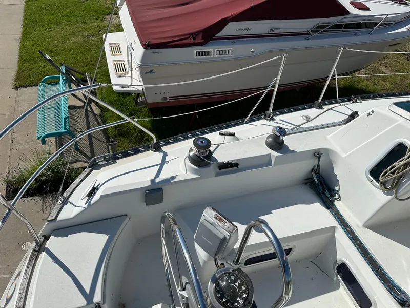 Slide: The Image of C&C 30 sailboat deck, 1989 model, with winches and railing, docked near another boat. - 13