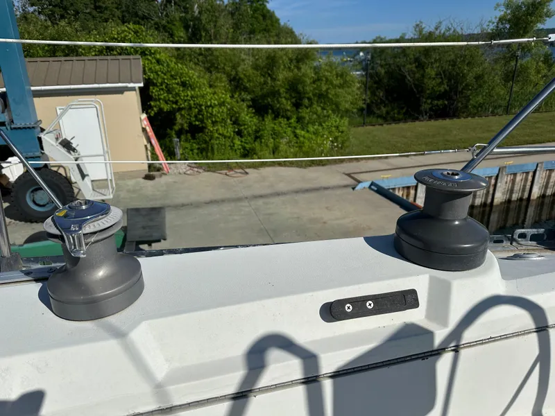 Slide: The Image of Winches on a 1989 C&C 30 sailboat deck, surrounded by greenery and a dock. - 16