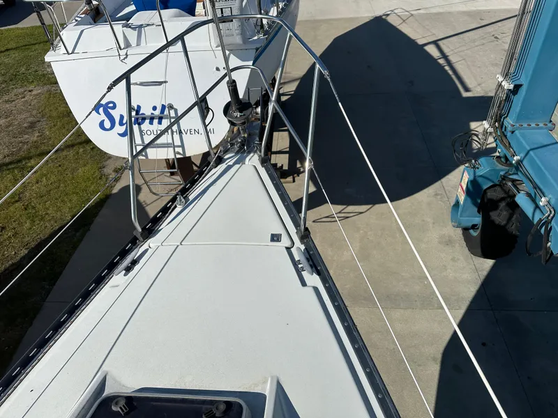 Slide: The Image of Bow view of a 1989 C&C 30 sailboat on a trailer, parked beside a blue vehicle. - 21