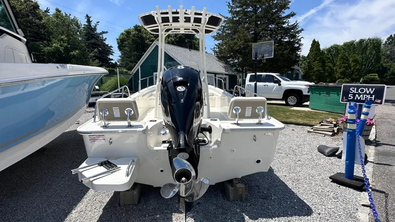 Slide: The Image of 2025 Boston Whaler 190 Montauk boat with outboard motor, parked on gravel. - 2