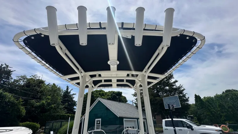 Slide: The Image of 2025 Boston Whaler 190 Montauk boat canopy with rod holders, set against a clear sky. - 23