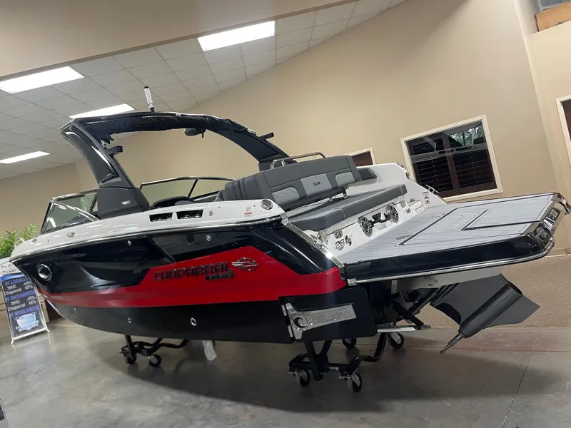 The Image of 2025 Chaparral 26 Surf boat in showroom, featuring sleek black and red design. - 0