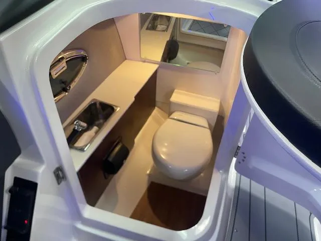 Slide: The Image of 2025 Chaparral 26 Surf boat interior bathroom with sink, toilet, and mirror. - 10