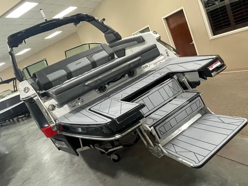 Slide: The Image of 2025 Chaparral 26 Surf boat with extended swim platform and seating in showroom. - 3