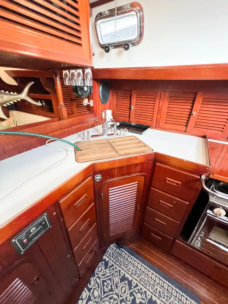 Slide: The Image of 1986 Tayana Vancouver 42 yacht interior with wooden cabinetry and compact kitchen area. - 23