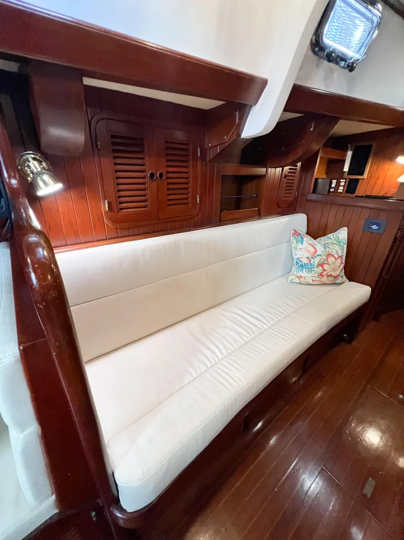 Slide: The Image of Interior of 1986 Tayana Vancouver 42 yacht with white cushioned seating and wooden paneling. - 49