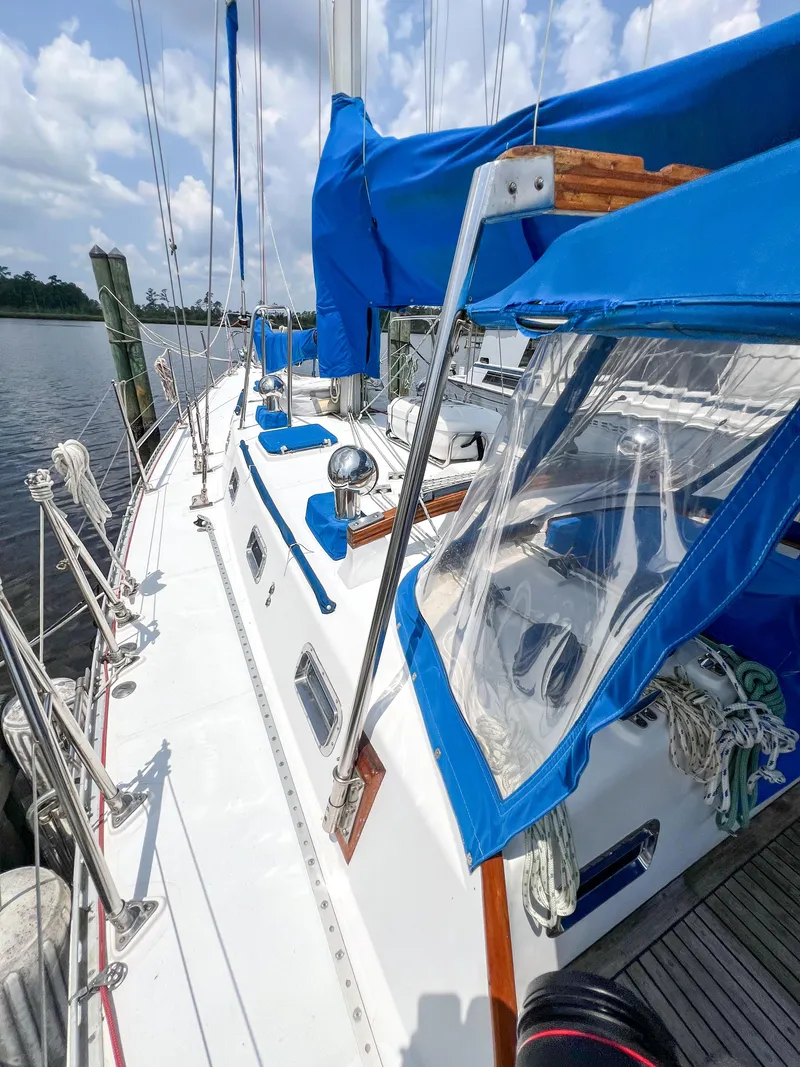 Slide: The Image of 1986 Tayana Vancouver 42 sailboat with blue covers docked by the water. - 8