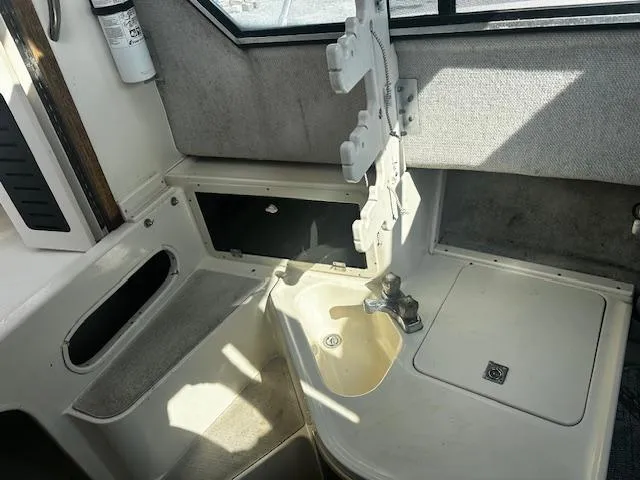 Slide: The Image of Interior of 1993 Grady-White Sailfish 252 boat, featuring a compact sink and storage area. - 14
