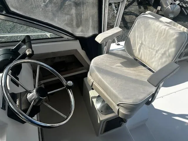 Slide: The Image of 1993 Grady-White Sailfish 252 helm with steering wheel and cushioned captain's chair. - 7