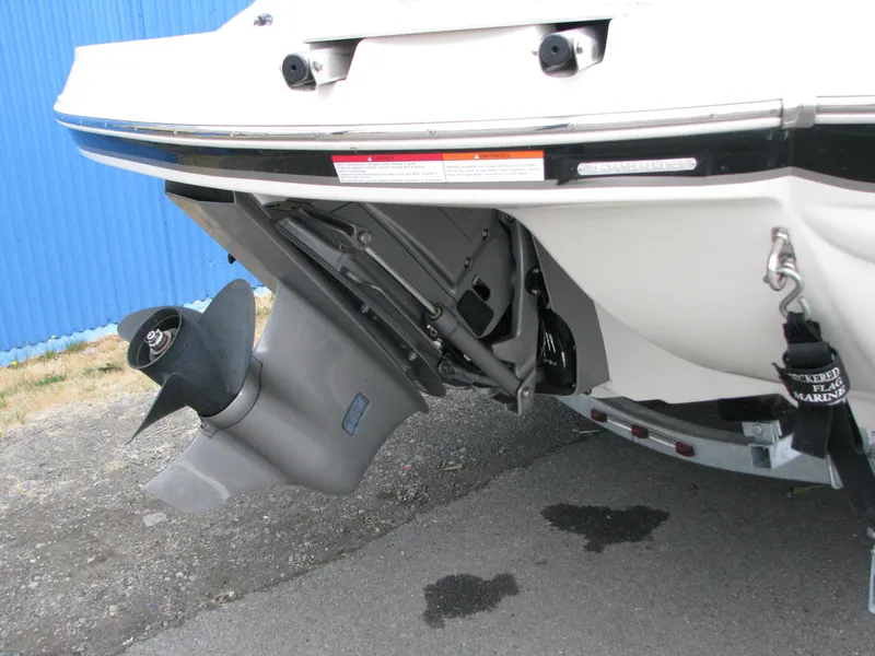 Slide: The Image of 2017 Stingray 215 CR boat stern with propeller and outdrive, parked on pavement. - 4