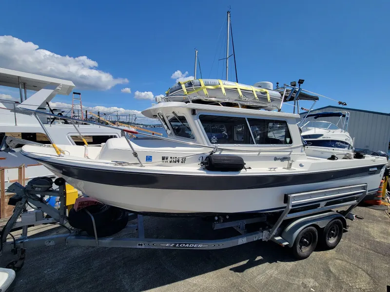 Slide: The Image of 2000 SeaSport 2400 XL Limited boat on trailer, docked under clear blue sky. - 0