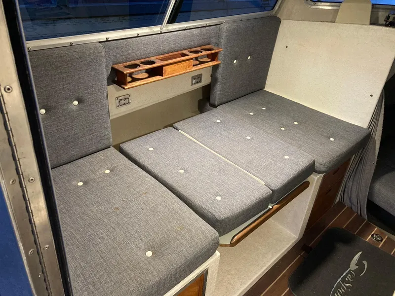 Slide: The Image of Interior seating of 2000 SeaSport 2400 XL Limited boat with gray cushions and wooden cup holder. - 19