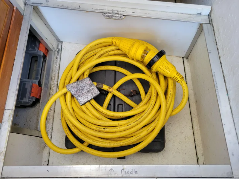 Slide: The Image of Yellow power cable stored in a compartment of a 2000 SeaSport 2400 XL Limited boat. - 32