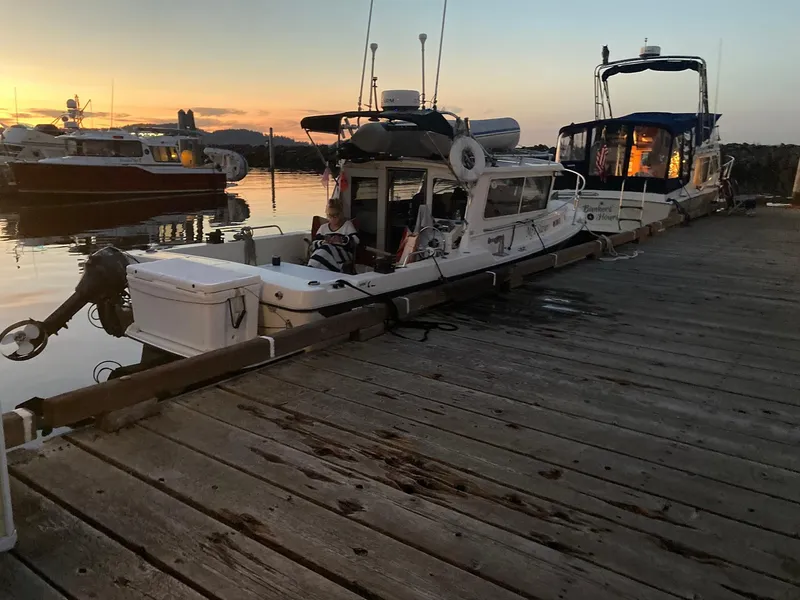 Slide: The Image of 2000 SeaSport 2400 XL Limited docked at sunset, with calm water and nearby boats. - 45