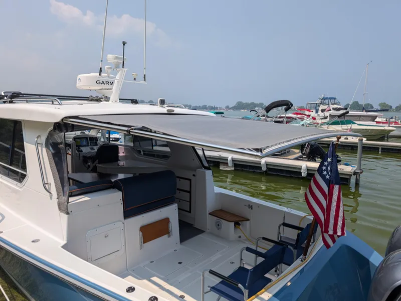 Slide: The Image of 2018 True North 34OE boat docked, featuring a shaded cockpit and American flag. - 24