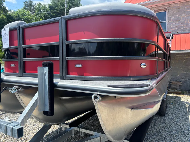 Slide: The Image of 2025 Bentley Pontoons 223 NAVIGATOR, red and black design, on a trailer outdoors. - 2