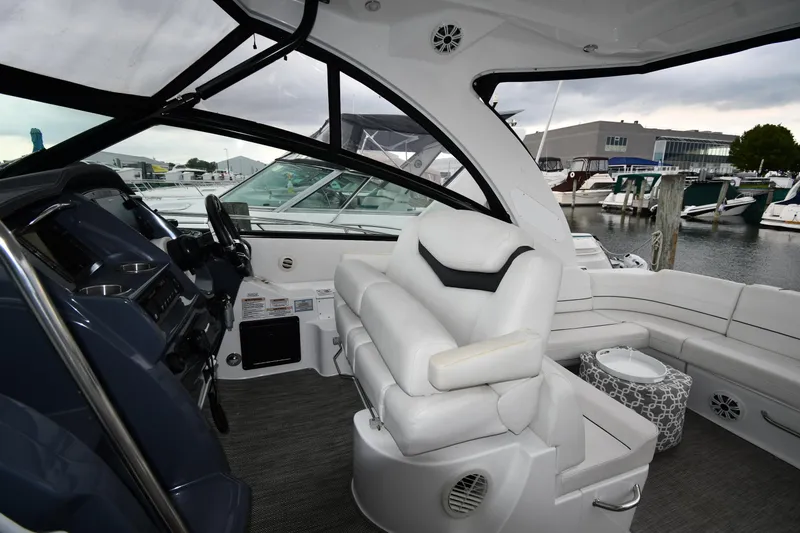 Slide: The Image of 2019 Cruisers Yachts 380 Express interior with helm, white seating, and marina view. - 16