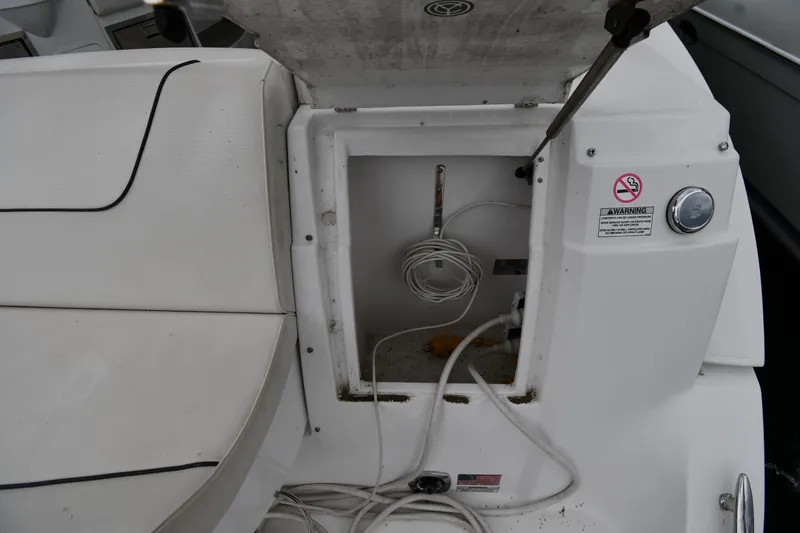 Slide: The Image of 2019 Cruisers Yachts 380 Express storage compartment with cables and warning labels. - 29
