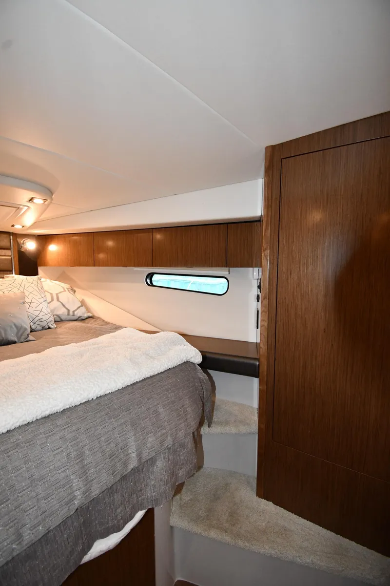 Slide: The Image of 2019 Cruisers Yachts 380 Express cabin interior with bed and wooden cabinetry. - 33