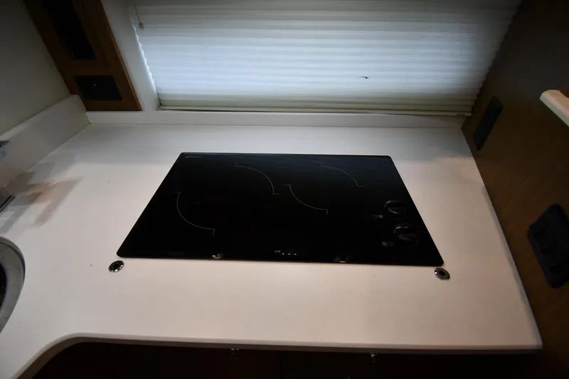 Slide: The Image of 2019 Cruisers Yachts 380 Express kitchen with sleek black cooktop and white countertop. - 46