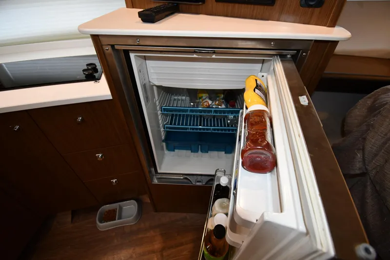 Slide: The Image of Open refrigerator in 2019 Cruisers Yachts 380 Express, stocked with condiments and beverages. - 48