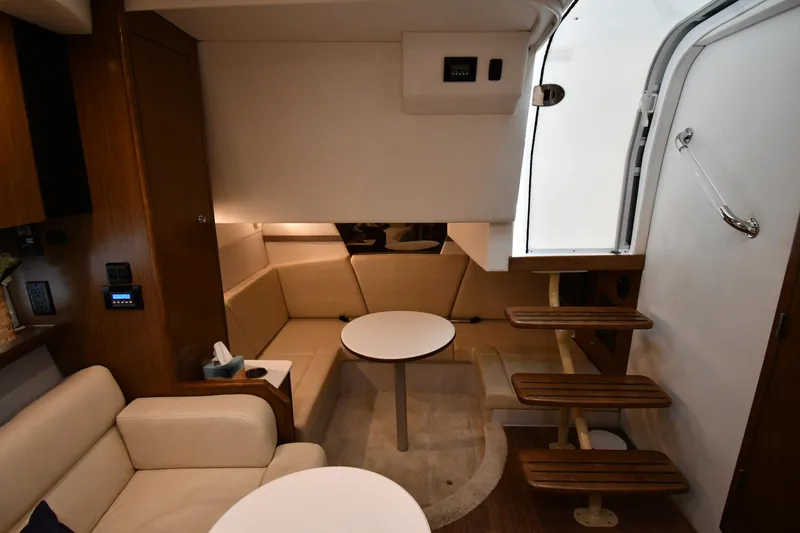 Slide: The Image of 2019 Cruisers Yachts 380 Express interior with cozy seating and wooden steps. - 49