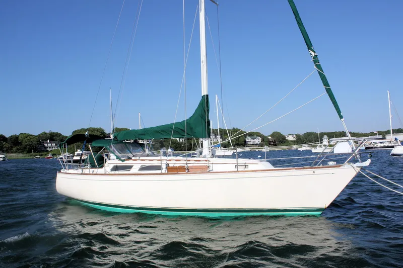 The Image of 1986 Sabre 34 MK II sailboat on water, green sails, clear sky background. - 0