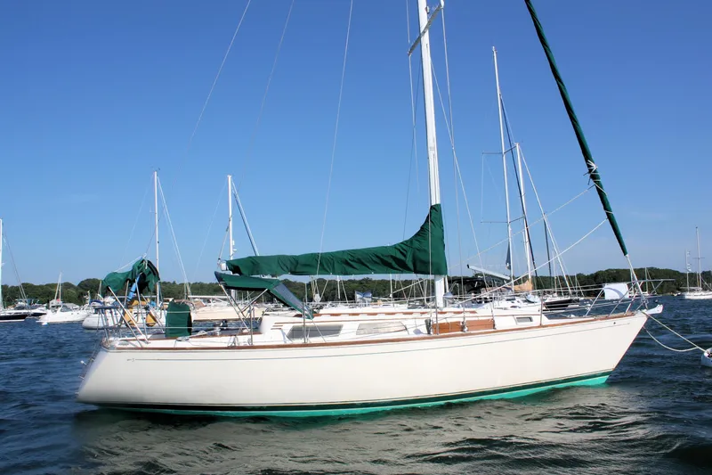Slide: The Image of 1986 Sabre 34 MK II sailboat with green covers, anchored in a marina. - 2