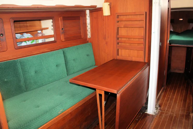 Slide: The Image of Interior of 1986 Sabre 34 MK II sailboat with green cushioned seating and wooden table. - 26