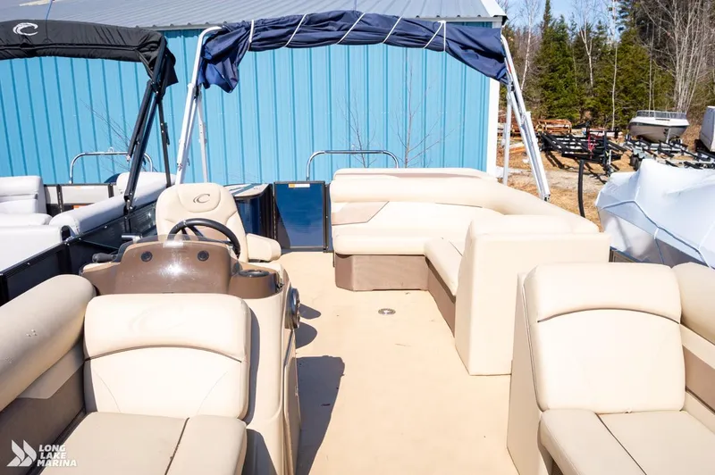 Slide: The Image of 2019 Crest CREST I 220 L pontoon boat with beige seating, parked near a blue building. - 8