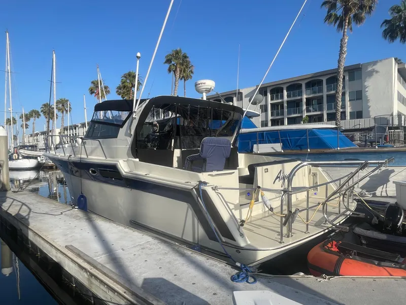 The Image of 1989 Californian Express yacht docked at marina with palm trees and blue sky. - 0