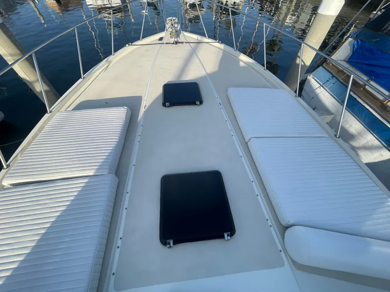 Slide: The Image of 1989 Californian Express boat deck with white cushions and hatches, docked at marina. - 4
