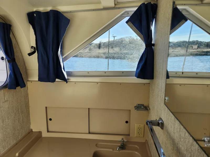 Slide: The Image of Interior of 1975 Bertram 28 Flybridge Cruiser with window view and blue curtains. - 11