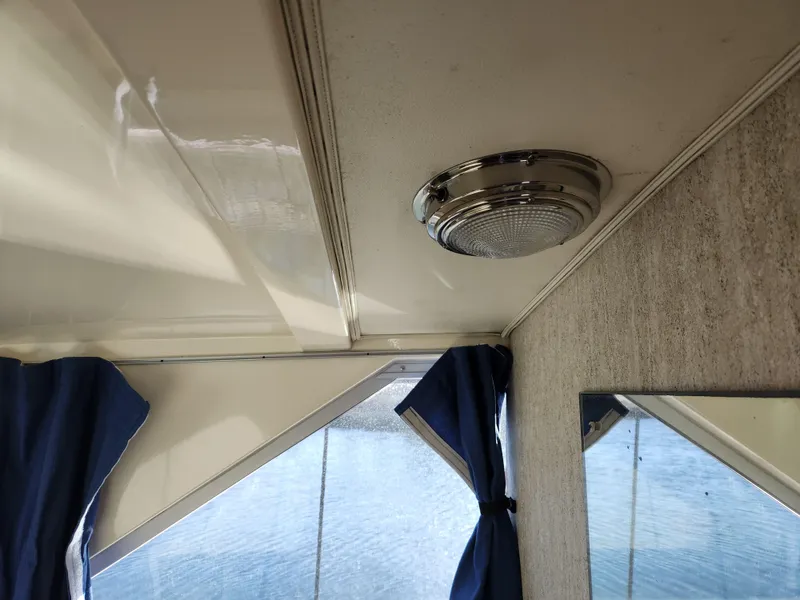 Slide: The Image of Interior of 1975 Bertram 28 Flybridge Cruiser with blue curtains and ceiling light. - 12