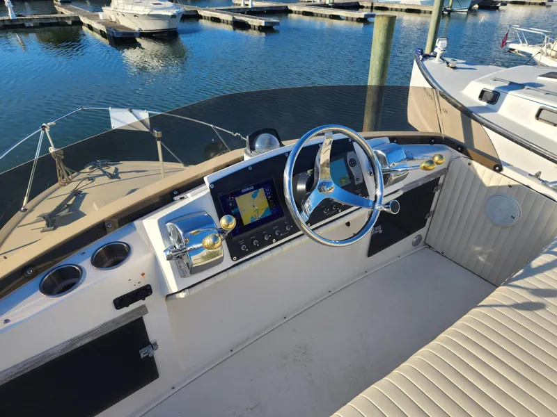 Slide: The Image of 1975 Bertram 28 Flybridge Cruiser helm with modern navigation, docked at marina. - 3