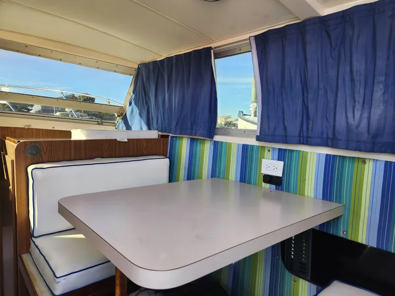 Slide: The Image of 1975 Bertram 28 Flybridge Cruiser interior with table, blue curtains, and striped wall. - 9