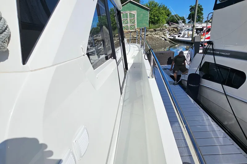 Slide: The Image of 2024 Beneteau Antares 12 yacht docked, side view with railing and marina background. - 17