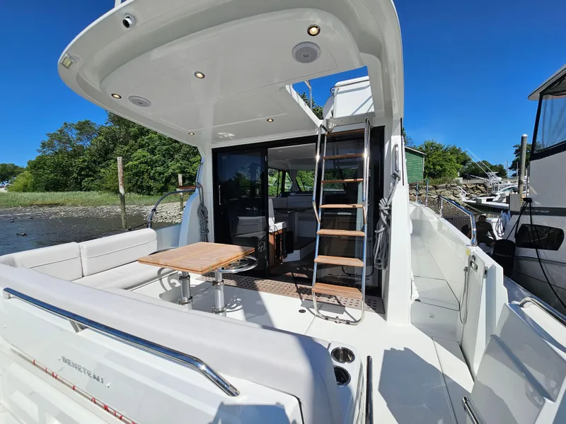 Slide: The Image of 2024 Beneteau Antares 12 yacht with spacious deck, seating, and ladder under clear blue sky. - 4