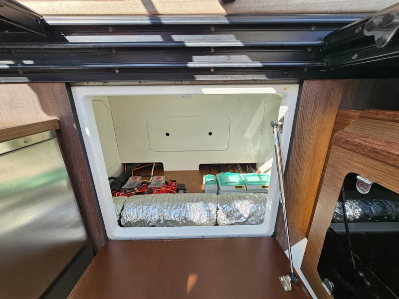Slide: The Image of 2024 Beneteau Antares 12 interior storage compartment with visible wiring and insulation. - 49