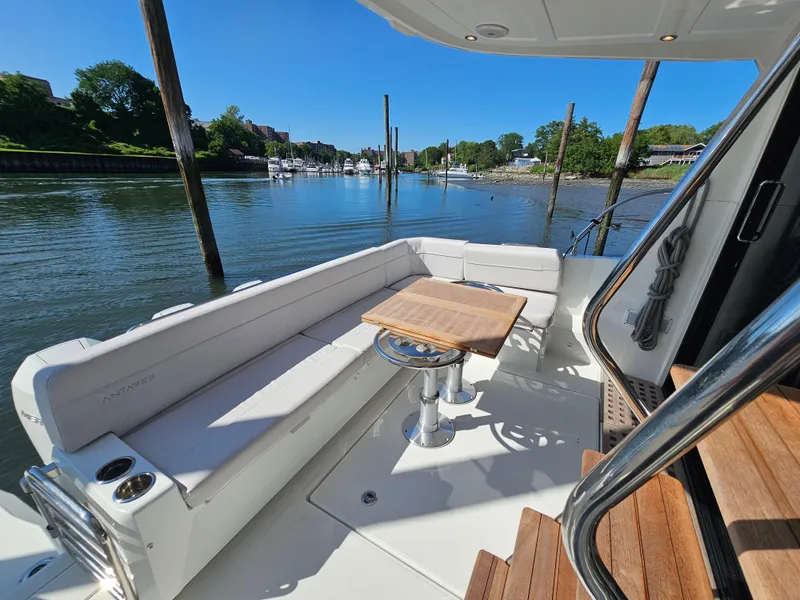 Slide: The Image of 2024 Beneteau Antares 12 yacht deck with seating and table, docked by a scenic river. - 5
