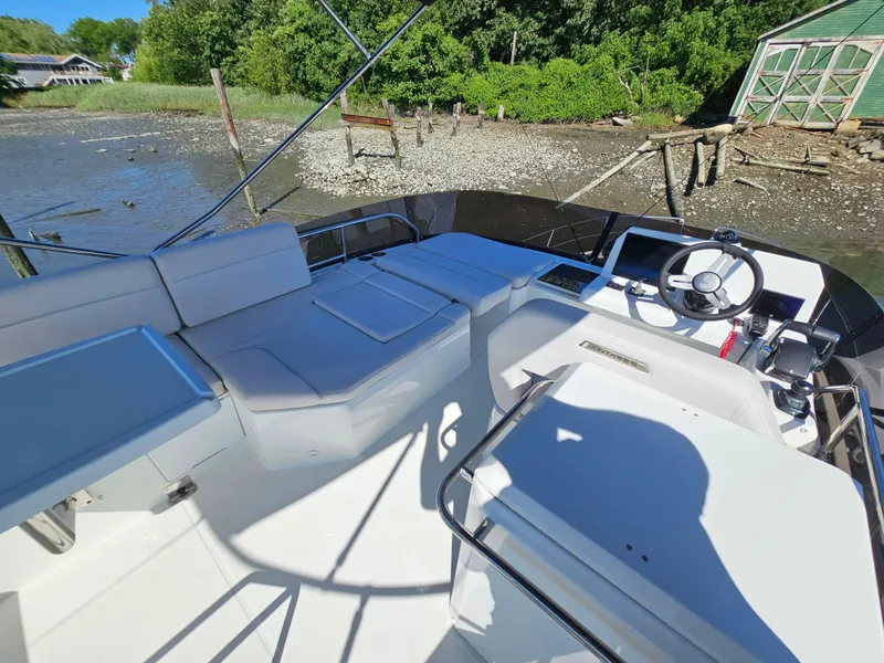 Slide: The Image of 2024 Beneteau Antares 12 boat interior with steering wheel and seating, docked near a shoreline. - 9