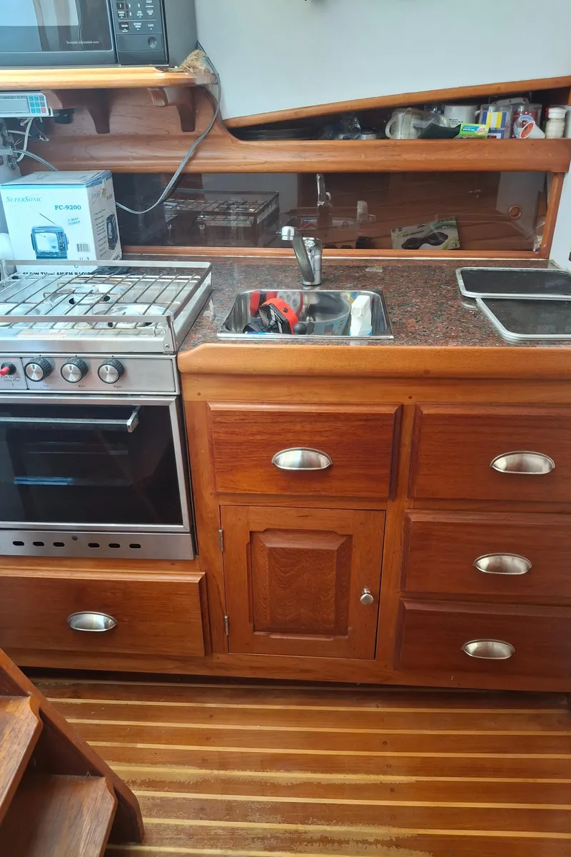 Slide: The Image of 2003 Duffy 35 Downeast Flybridge Cruiser kitchen with stove, sink, and wooden cabinetry. - 17