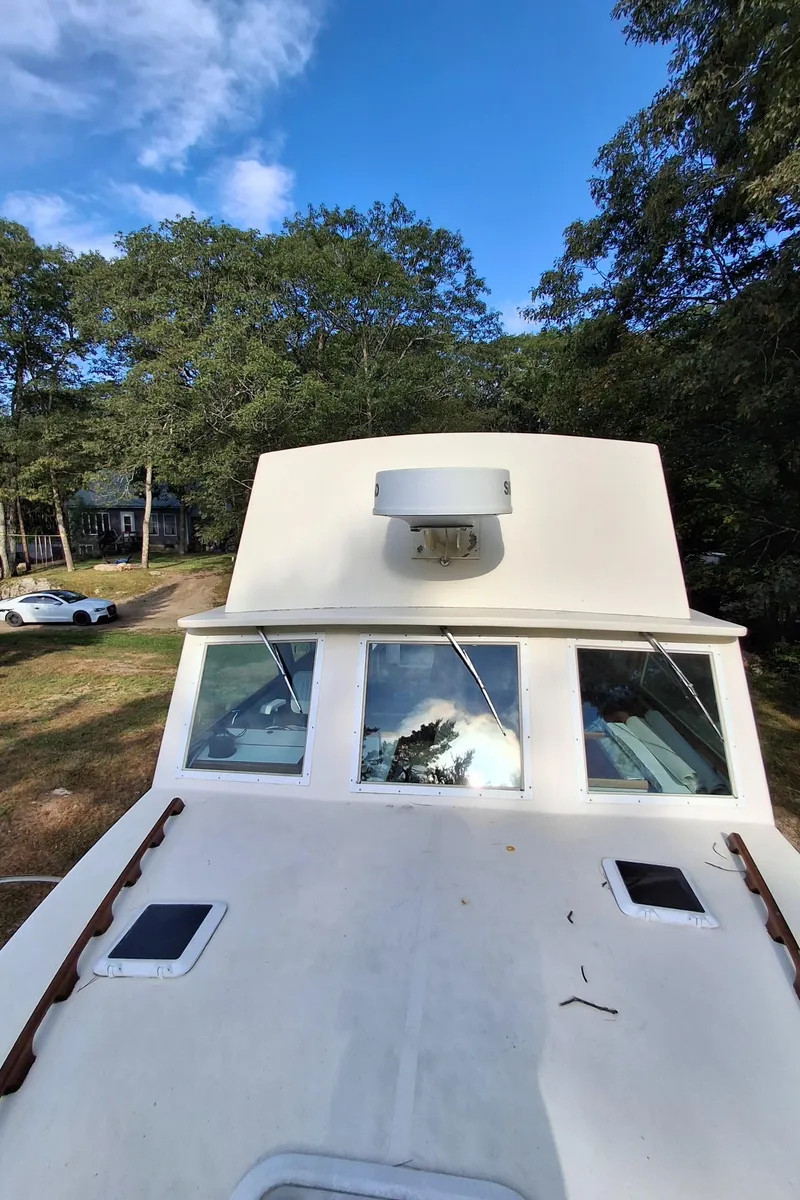 Slide: The Image of 2003 Duffy 35 Downeast Flybridge Cruiser on land, surrounded by trees and a car. - 25