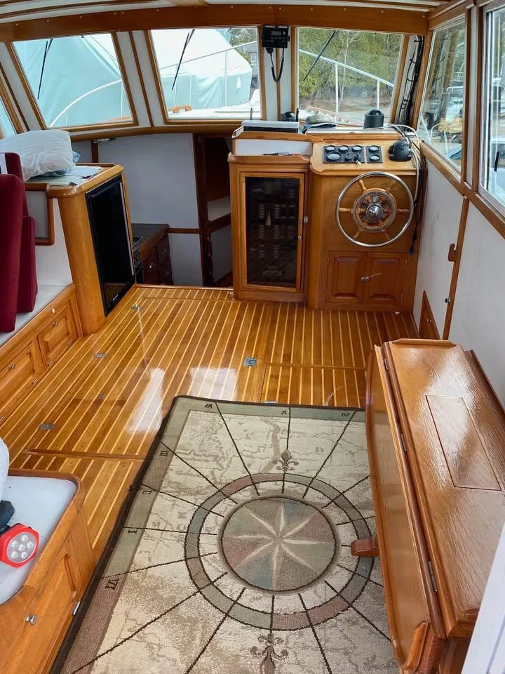 Slide: The Image of 2003 Duffy 35 Downeast Flybridge Cruiser interior with wooden flooring and nautical-themed rug. - 4