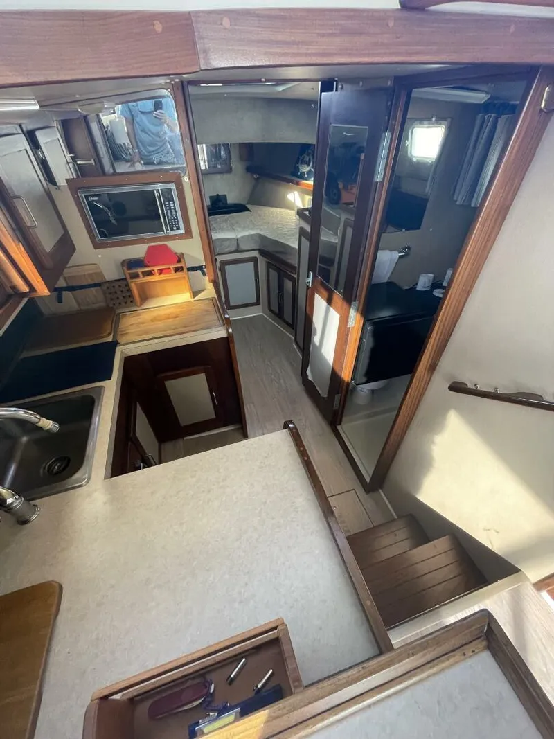 Slide: The Image of Interior of 1984 Mainship MK III boat, featuring kitchen and living area with wood accents. - 12