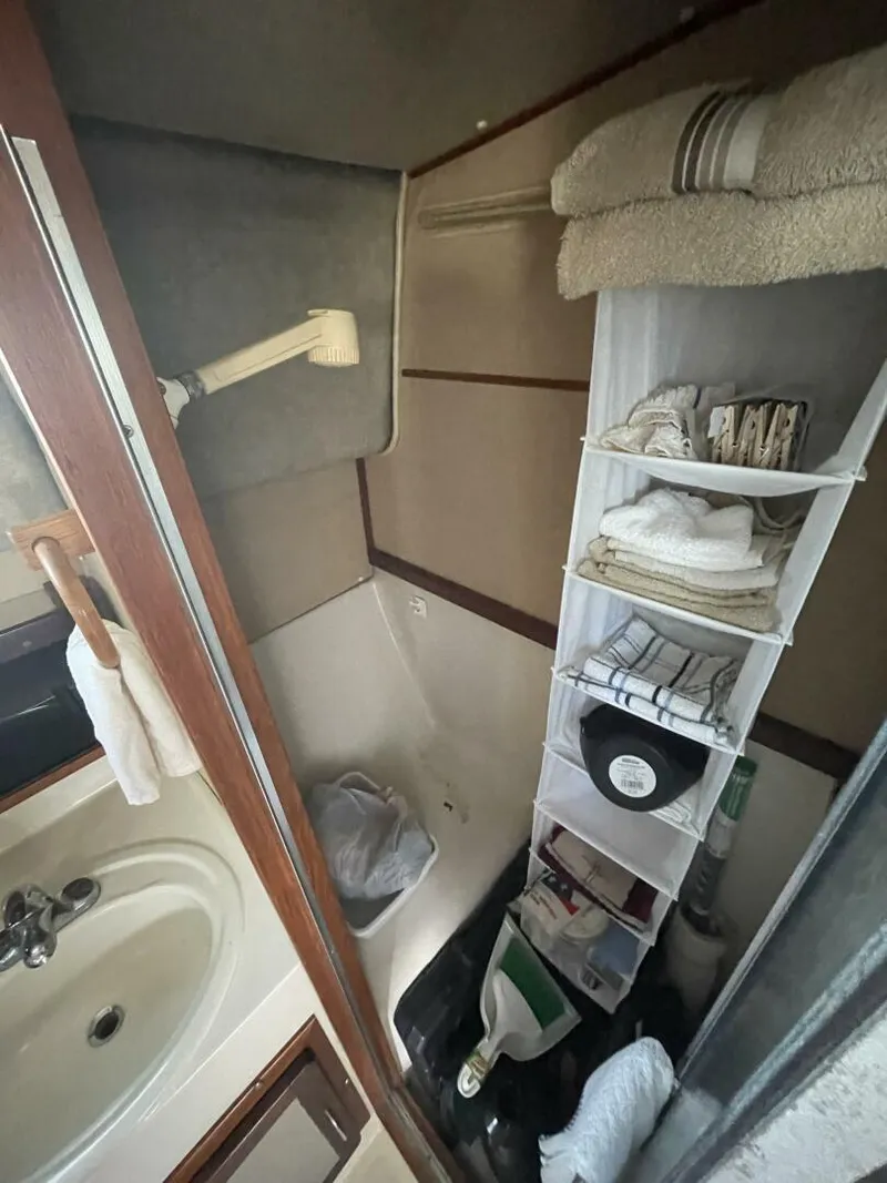 Slide: The Image of 1984 Mainship MK III bathroom with sink, shower, and storage shelves. - 14