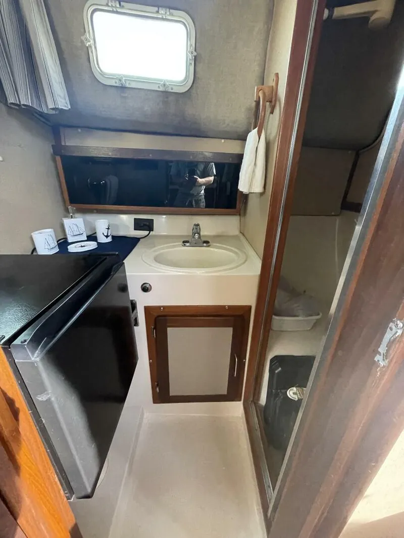 Slide: The Image of 1984 Mainship MK III boat interior with sink, fridge, and storage. - 15