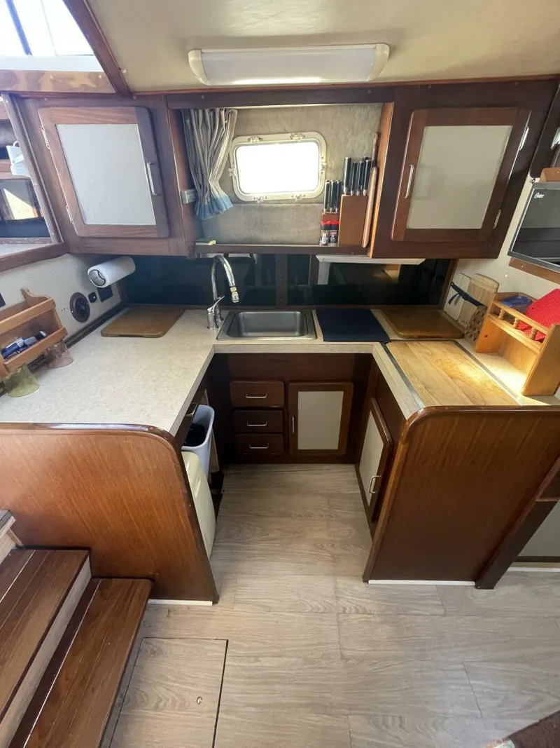 Slide: The Image of 1984 Mainship MK III boat kitchen with wooden cabinets, sink, and countertop. - 16