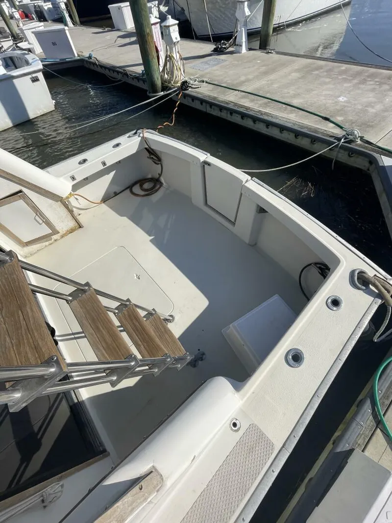 Slide: The Image of 1984 Mainship MK III boat docked, featuring a clean deck and wooden steps. - 20