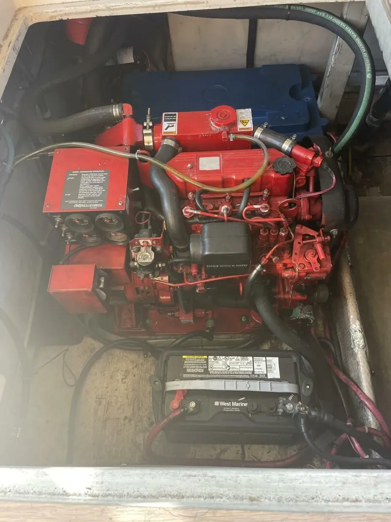 Slide: The Image of Engine compartment of a 1984 Mainship MK III with visible red engine and battery. - 34